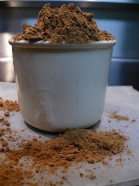 Measuring cup overflowing with natural cocoa powder.