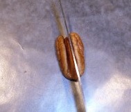 Cutting pecan in half length-wise to make turtle legs.