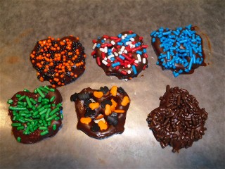 Six chocolate covered pretzels decorated with sprinkles.