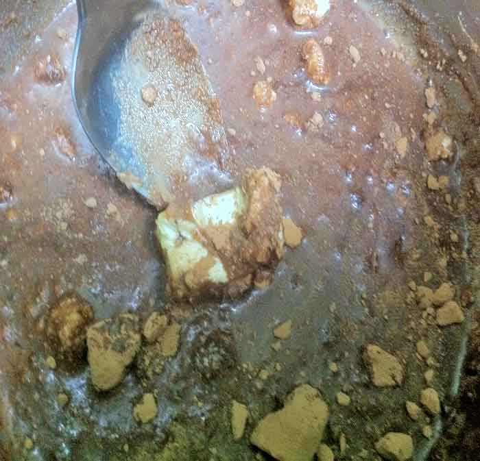 Lumps of cocoa and partially melted margarine being heated and stirred.